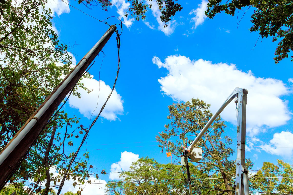 An electrical pole is repaired by technician using bucket lift following hurricane