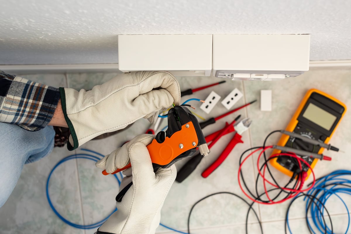 Electrician worker with wire stripper preparing cables