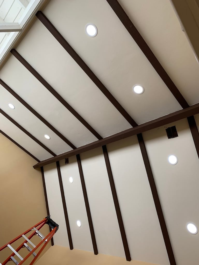 Modern ceiling with dark wooden beams, recessed lighting, and skylight