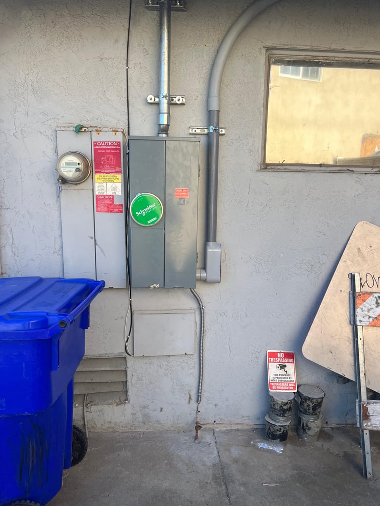 Residential electrical panel mounted on concrete wall with gray pipes