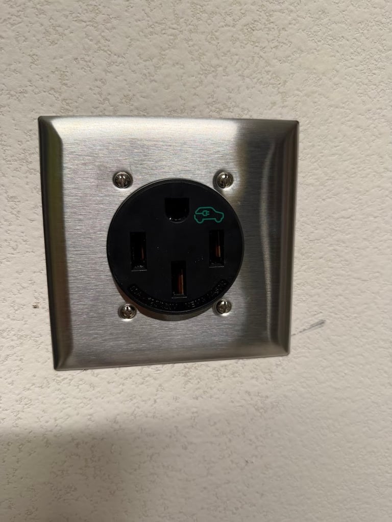 Brushed metal wall-mounted EV charging outlet with black circular connector and green car icon