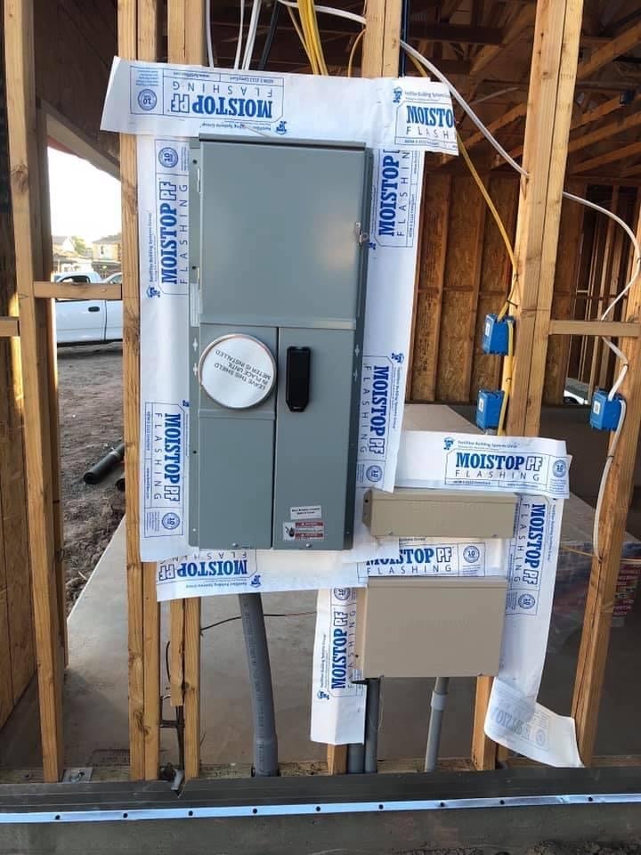 Gray electrical panel wrapped in Moistop moisture barrier during construction framing with wooden studs and blue conduit